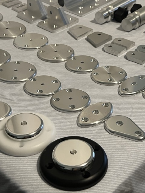 Assortment of machined aluminum mounting plates, brackets, and specialty components arranged on a work surface.