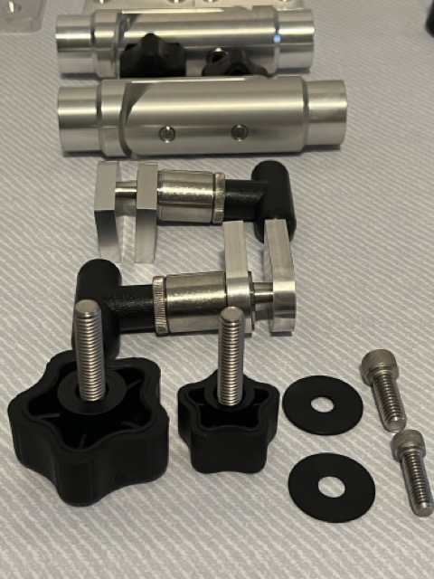 Grouped aluminum components including cylindrical joints, adjustable brackets, hand knobs, and fasteners laid out as a set.