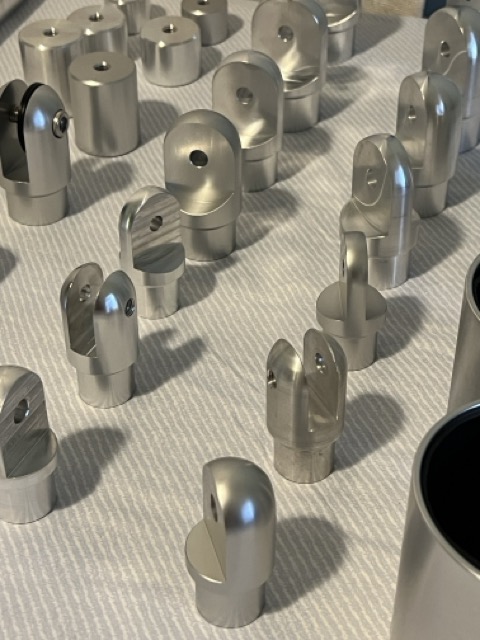 Rows of machined aluminum eye ends, jaw fittings, and related components on a work surface.